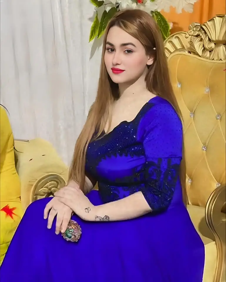 Woman with long light-brown hair in a blue dress with black lace trim, seated on an ornate gold chair
